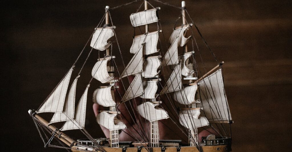 A hand in denim holds a vintage wooden model ship against a dark background.