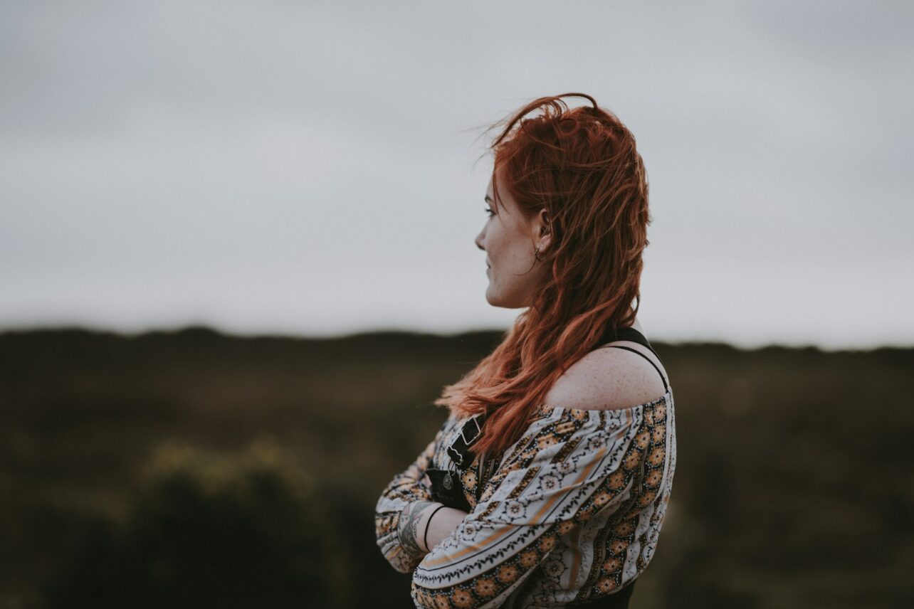 woman in white, orange, and black floral off-shoulder shirt crossing arms